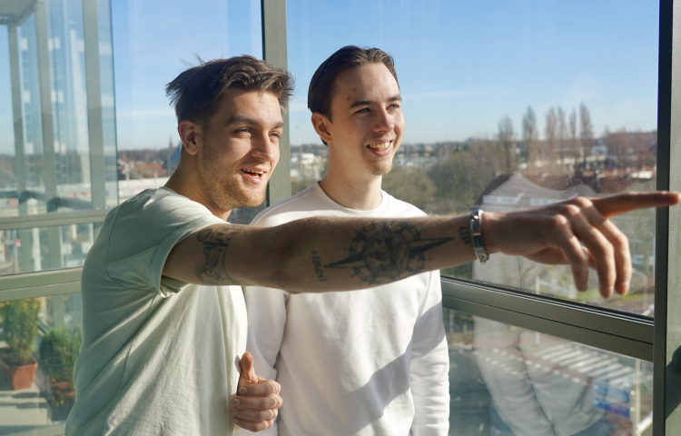 Yoshua en Rick voor het raam in hun woning aan het Maanplein