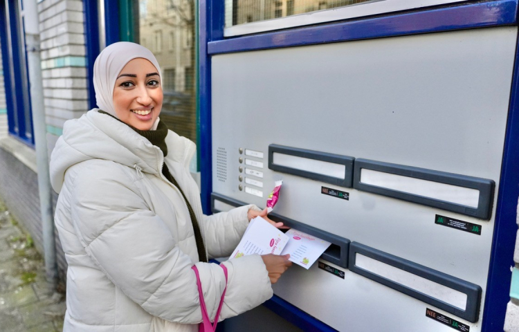 Fatima straatambassadeur doet een briefje door een brievenbus