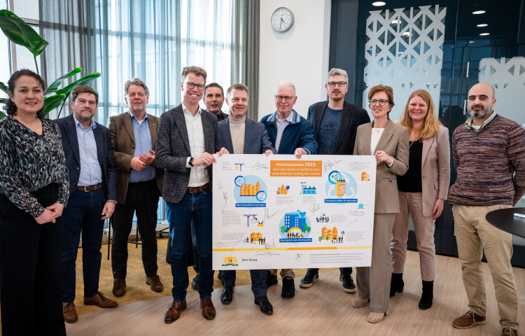 Groepsfoto van Martijn Balster en Gijsbert van Herk met een bord van de prestatieafspraken in handen met daarom heen alle woonpartners