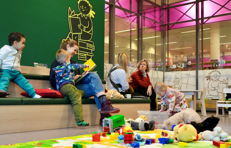 Moeders en kinderen spelen en lezen bij MIM